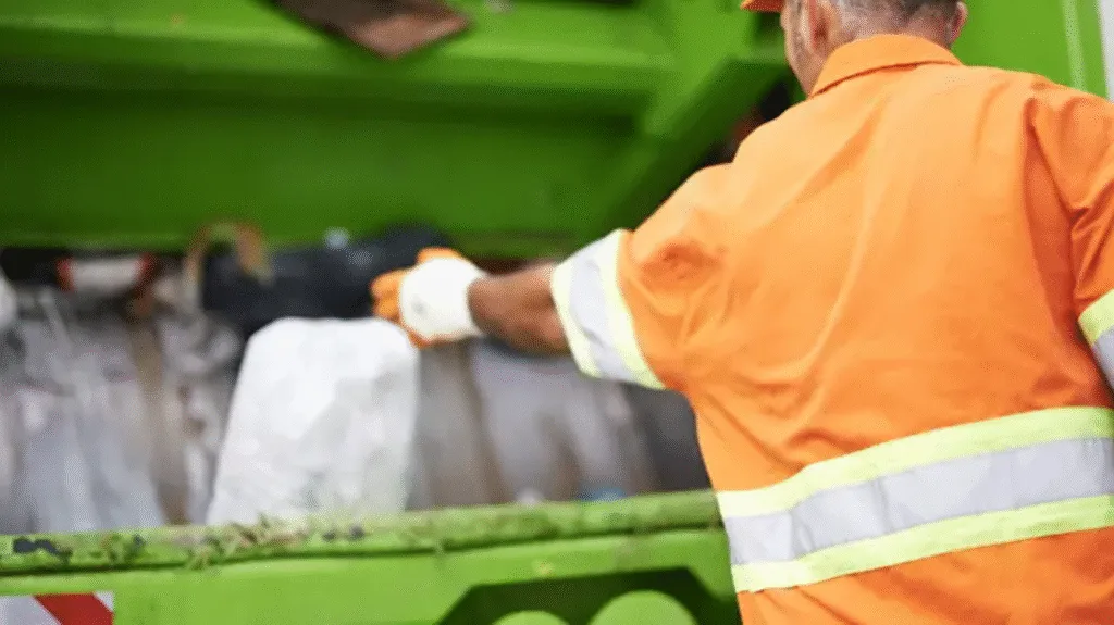 waste management worker putting trash in the truck